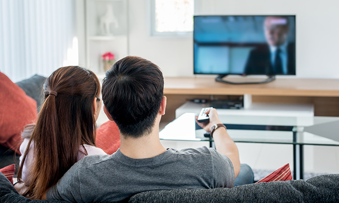 Rear view of Asian couple watching television in living room